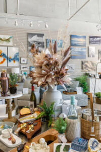 Vase with colorful flowers on Coastal Cottage of Amelia wooden table indoors, with wall visible in background.